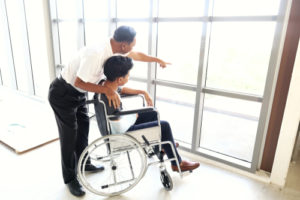 A child in a wheelchair looking out a window with an adult