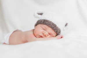 baby sleeping on belly in white hat