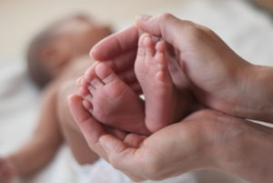 woman holding newborn’s feet