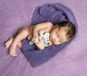 baby in purple hugging stuffed animal
