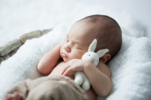 newborn baby sleeps with stuffed rabbit toy