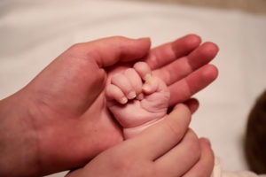 mother’s hand holding newborn