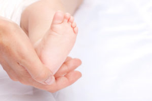 mother’s-hand-cupping-baby’s-left-foot