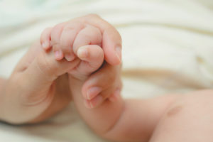 newborn holding mother’s thumb