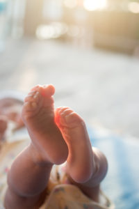 newborn in sunshine with feet in foreground