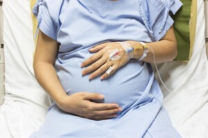 A close-up of a pregnant woman holding her stomach.
