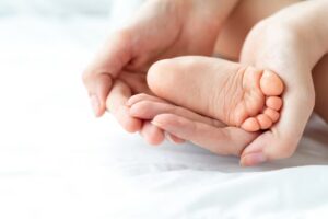 A new parent holding the feet of a baby who suffered a birth injury, wondering how common they are.