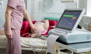 Pregnant woman in an electrocardiograph check-up, who is wondering what recurrent late decelerations are.