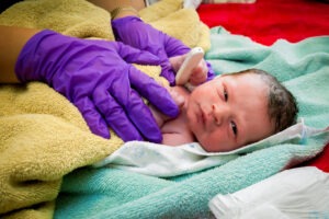 A medical professional administering an APGAR score test on a newborn infant.